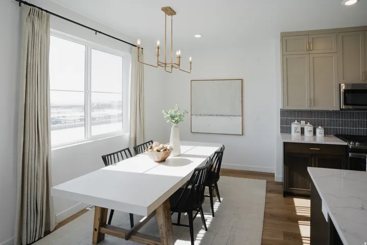 Recessed lighting, gold-tone chandelier, wood-finish flooring, two-tone cabinetry, and a dark tile backsplash