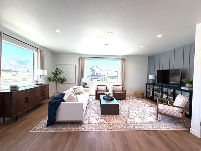 Wood-finish flooring, recessed lighting, expansive windows, decorative wall paneling, and a built-in media console