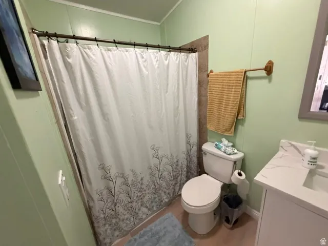 Shower with tile surround, wood-finish flooring, and single vanity with integrated sink