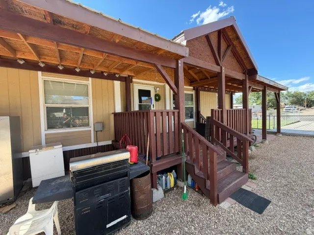 Covered porch entry featuring wood-finish railings and steps