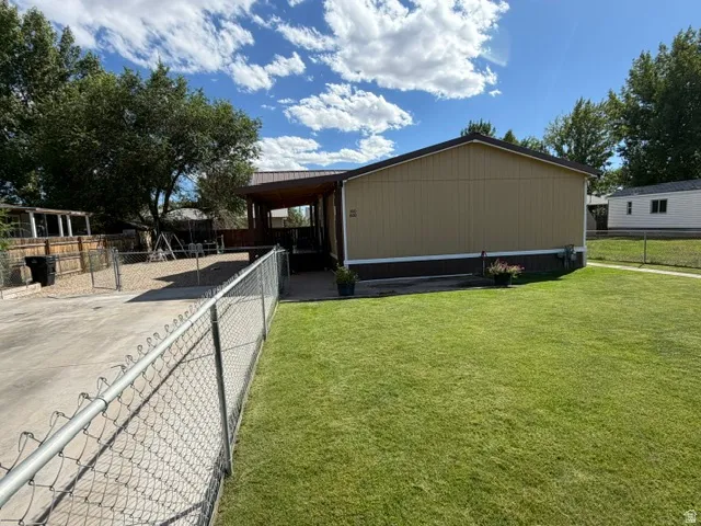 Expansive lawn area, chain link fencing, gravel hardscaping, covered patio, and mature trees