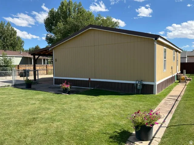 Expansive grassy yard with a concrete pathway and a covered patio structure