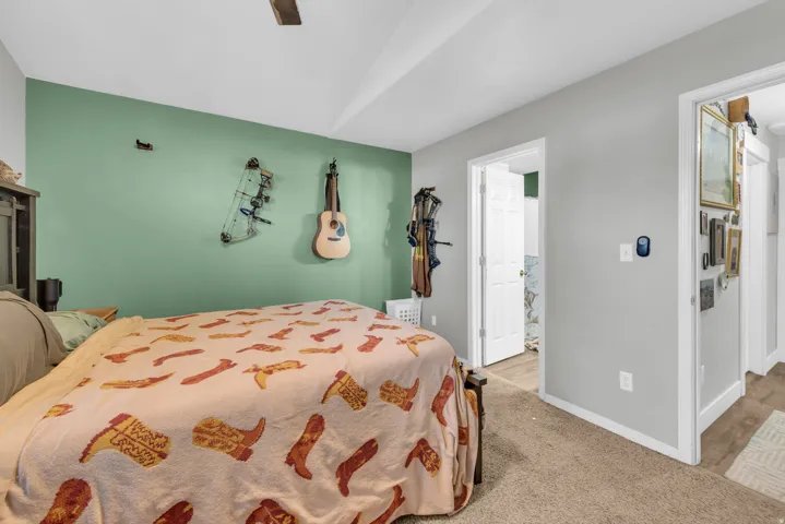 Vaulted ceiling, ceiling fan, neutral carpet flooring, white trim, and white paneled doors
