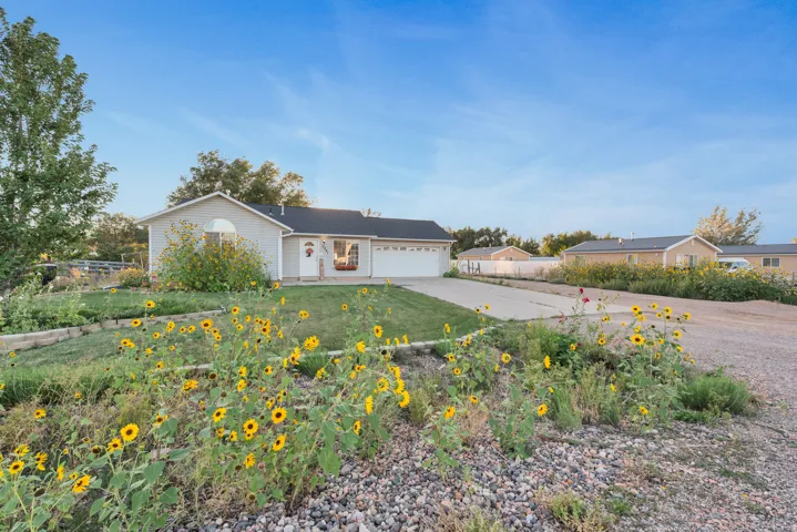 Light gray exterior with an attached garage, paved driveway, and manicured front lawn