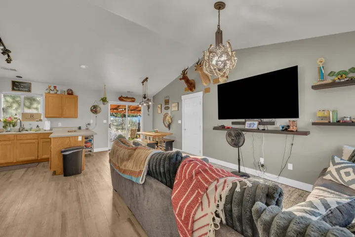 Vaulted ceiling, wood-finish flooring, light wood cabinetry, kitchen island with counter seating, sliding glass door