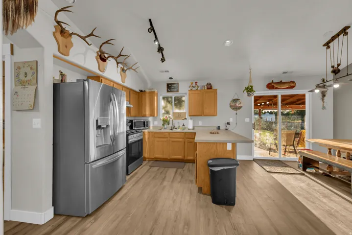 Kitchen featuring wood-finish flooring, light wood cabinetry, a stainless steel refrigerator, and a sliding glass door leading to an outdoor space