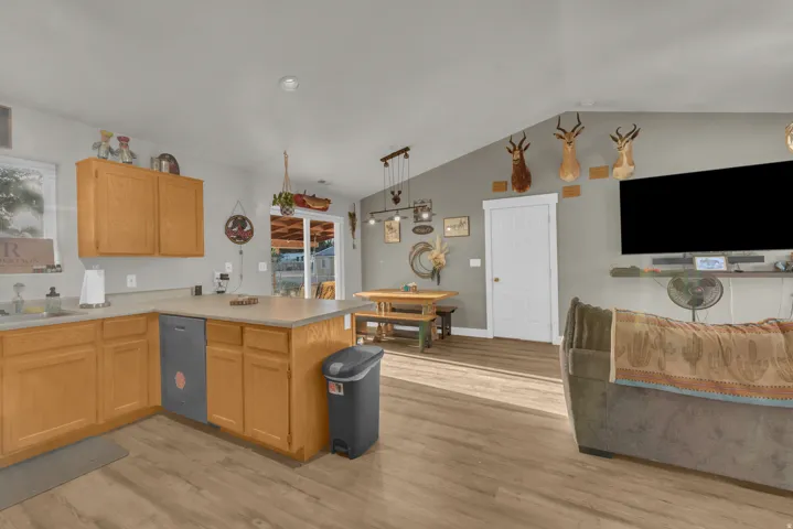Kitchen island with integrated dishwasher, wood-finish flooring, vaulted ceiling, and sliding glass door
