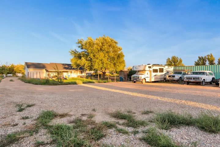 Expansive gravel parking area with a single-story residence featuring a covered porch