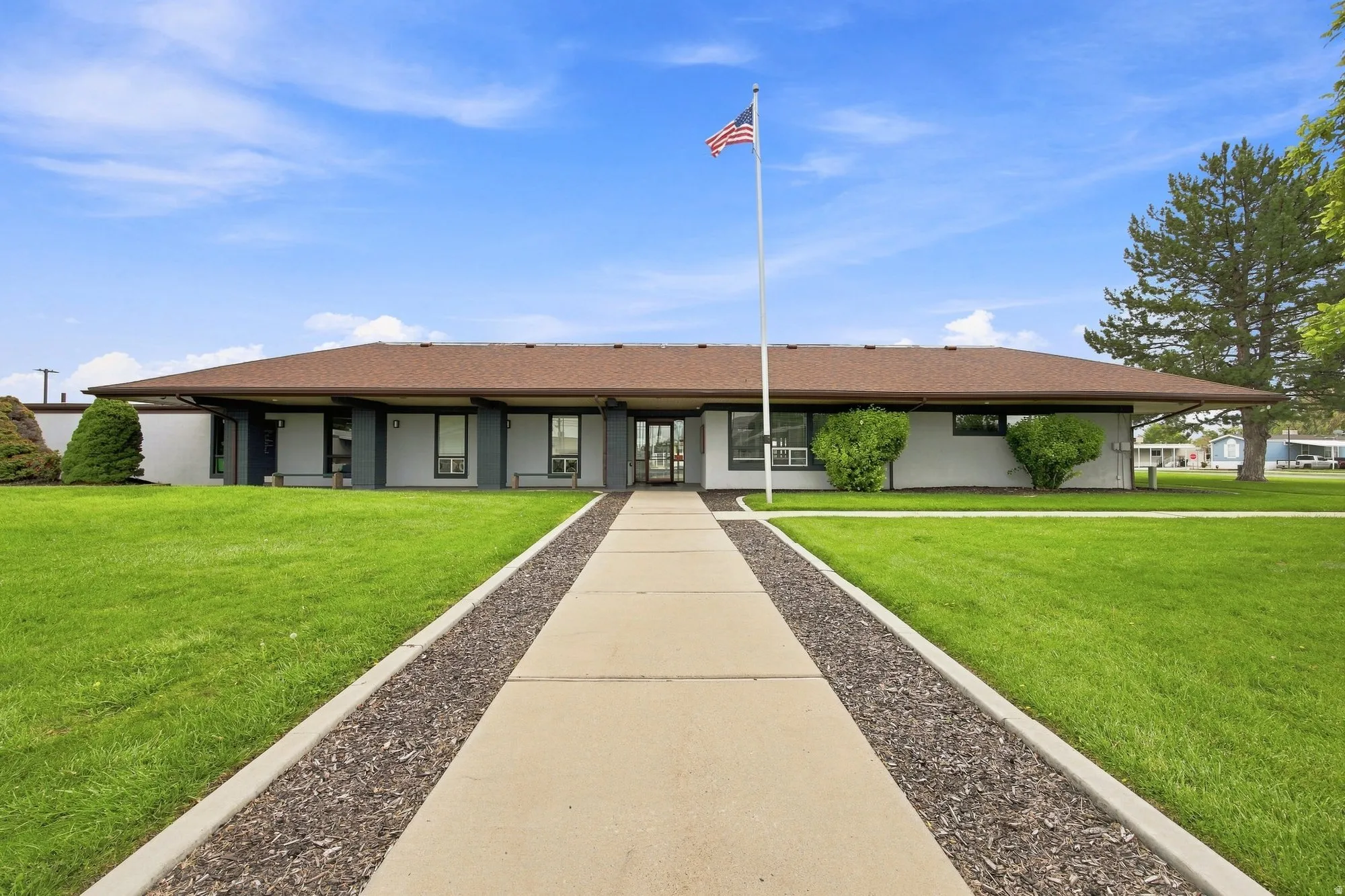 Single-story exterior with a brown shingle roof, light-colored siding, and dark trim accents