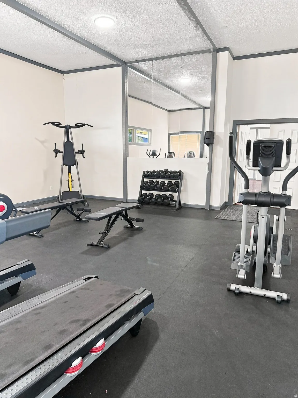 Fitness area featuring rubber flooring, recessed lighting, and mirrored wall panels