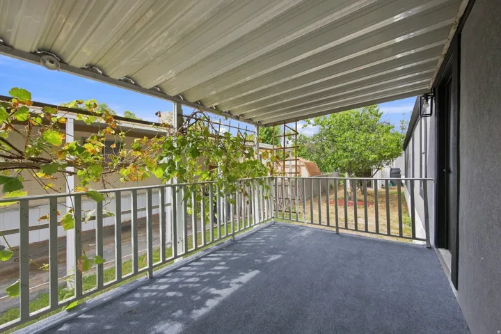 Covered patio with a corrugated roof, metal railings, and an exterior wall lantern