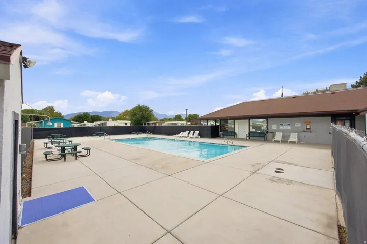 Outdoor swimming pool with a concrete surround, enclosed by a perimeter fence