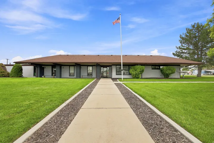 Single-story exterior with a brown shingle roof, light-colored siding, and dark trim accents