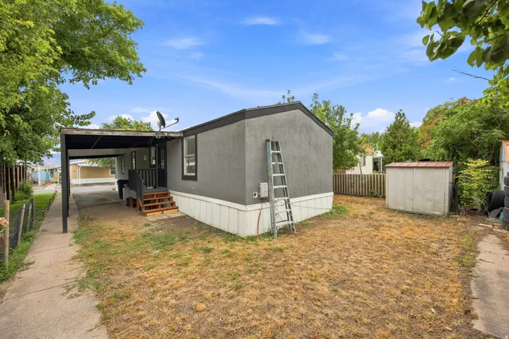 Carport with an attached storage shed, featuring a concrete walkway and wood-finish steps