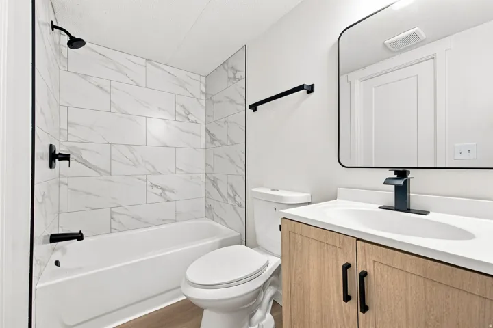 Tub/shower combination with white subway tile surround, matte black fixtures, and a glass partition