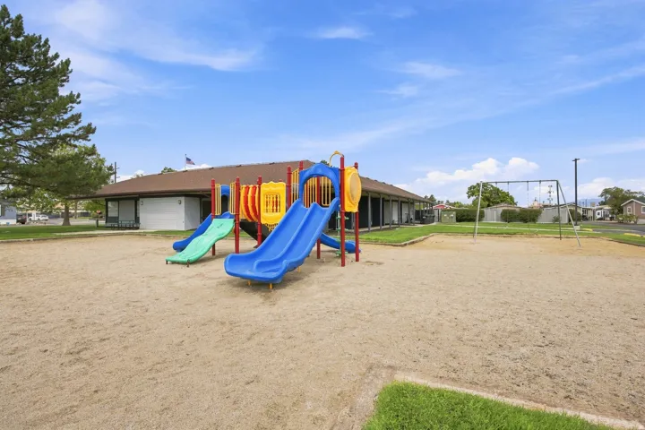 Outdoor play structure with multiple slides and a swing set on a sand surface