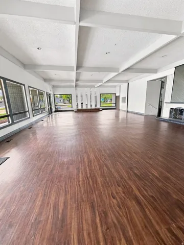 Expansive open-concept room featuring wood-finish flooring, numerous windows, and a coffered ceiling with recessed lighting