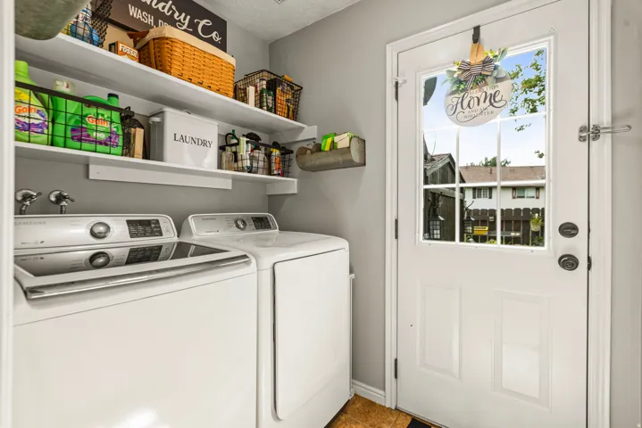 Dedicated laundry space with wall-mounted shelving, a full-lite exterior door, and durable flooring