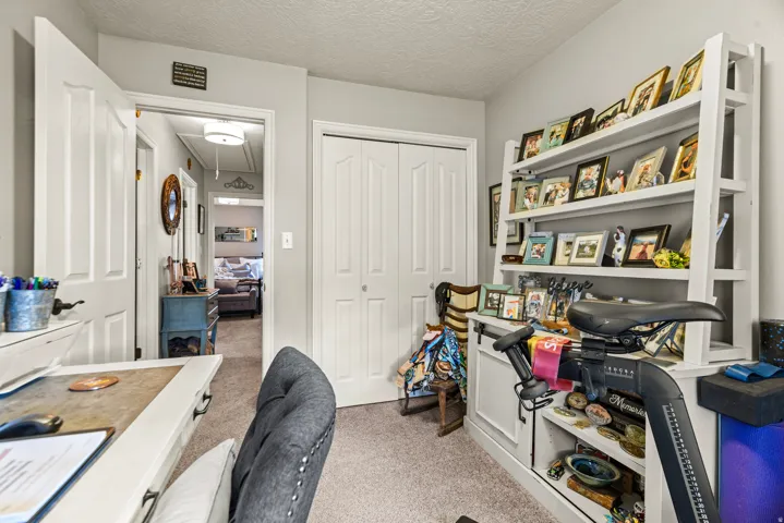Carpeted room with a paneled door, built-in shelving, and a dual bi-fold closet