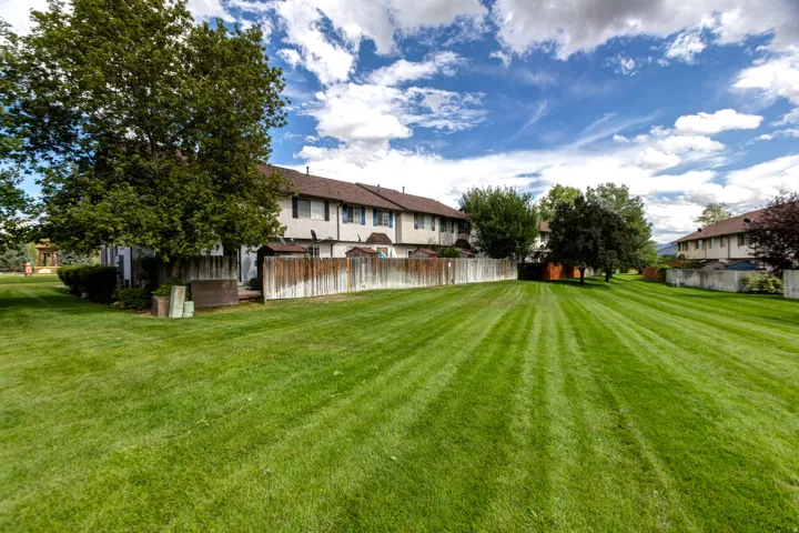 Expansive green space featuring mature trees and a perimeter fence