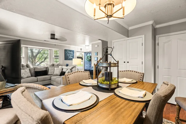 Wood-finish dining table with upholstered chairs, crown molding, and double panel doors