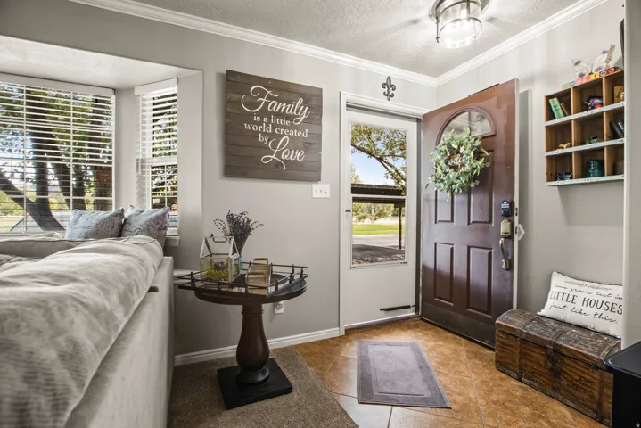 Paneled entry door with an arched lite, tiled flooring, and a built-in wall shelf