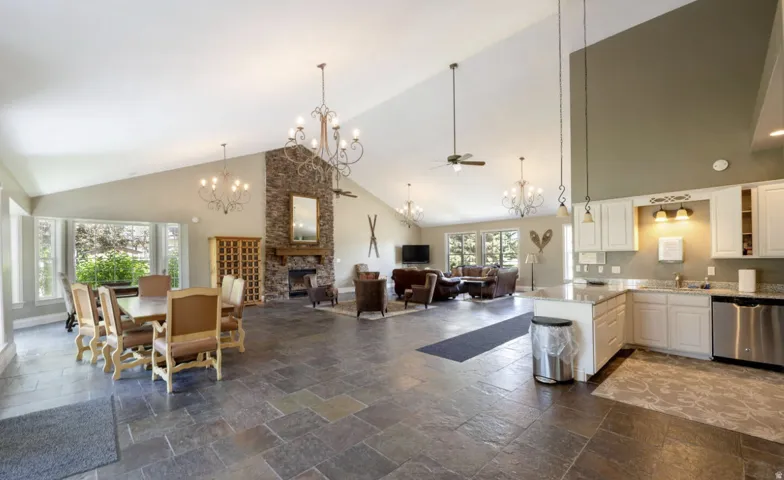 Vaulted ceilings, a stone-clad fireplace, and expansive bay windows create a sophisticated atmosphere