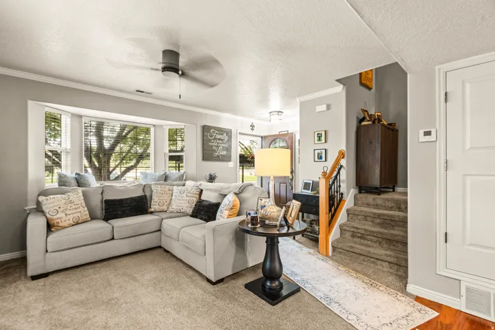 Recessed bay window, ceiling fan, carpeted flooring, wood-finish handrail, and white paneled door