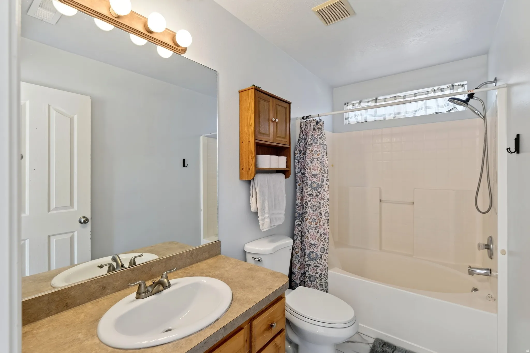 Single vanity with an oval sink, brushed nickel faucet, and a large wall-mounted mirror