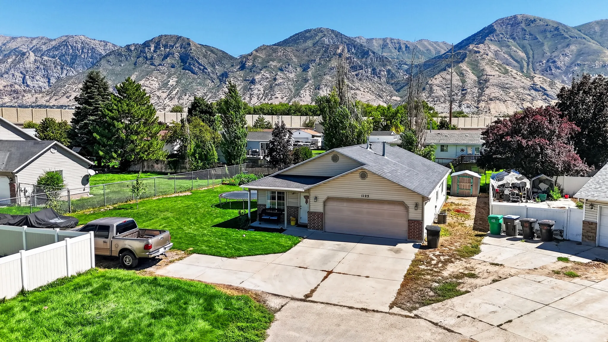 Single-story residence featuring an attached garage, paved driveway, and mature landscaping