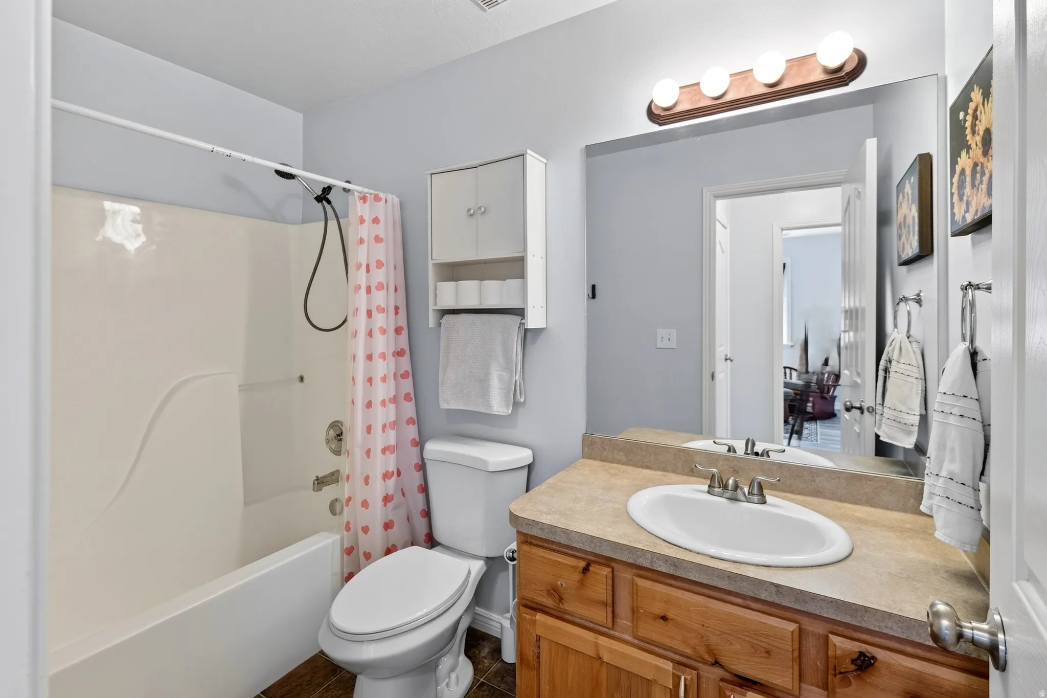 Bathroom featuring a built-in vanity with a single basin sink, a wall-mounted mirror, a tub/shower combination, and a toilet