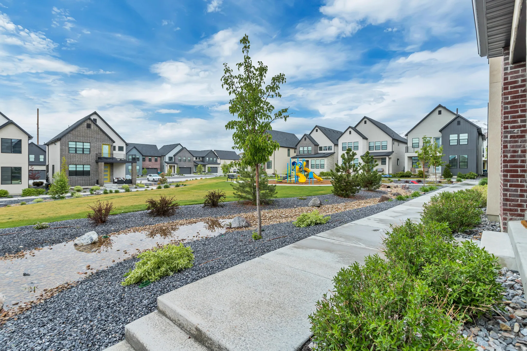 Community green space featuring a playground, manicured lawn, and paved walkways