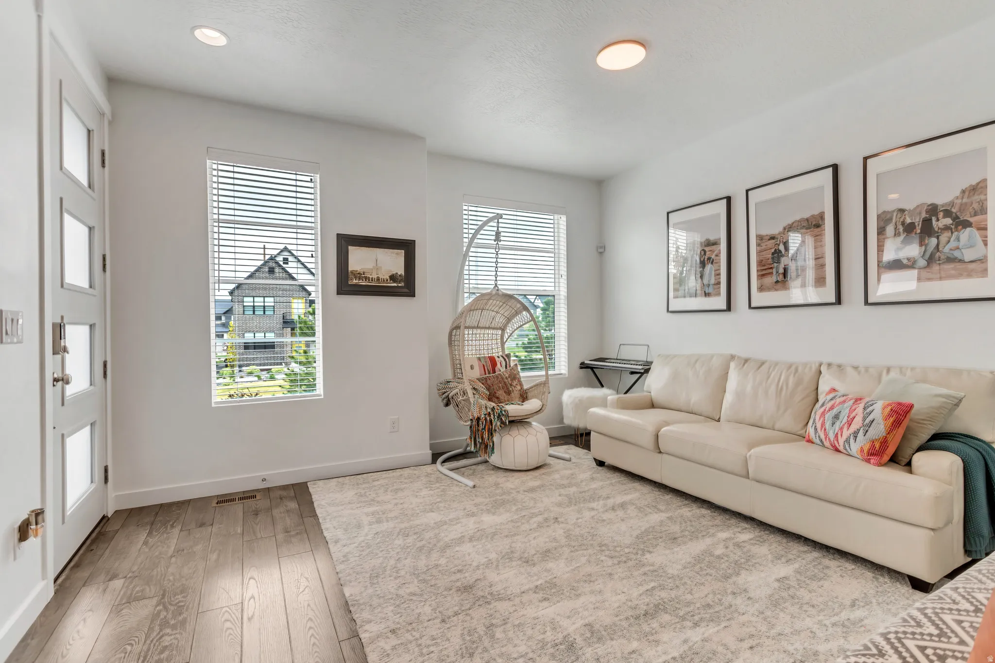 Recessed lighting, wood-finish flooring, white walls, and a multi-paneled entry door with frosted glass