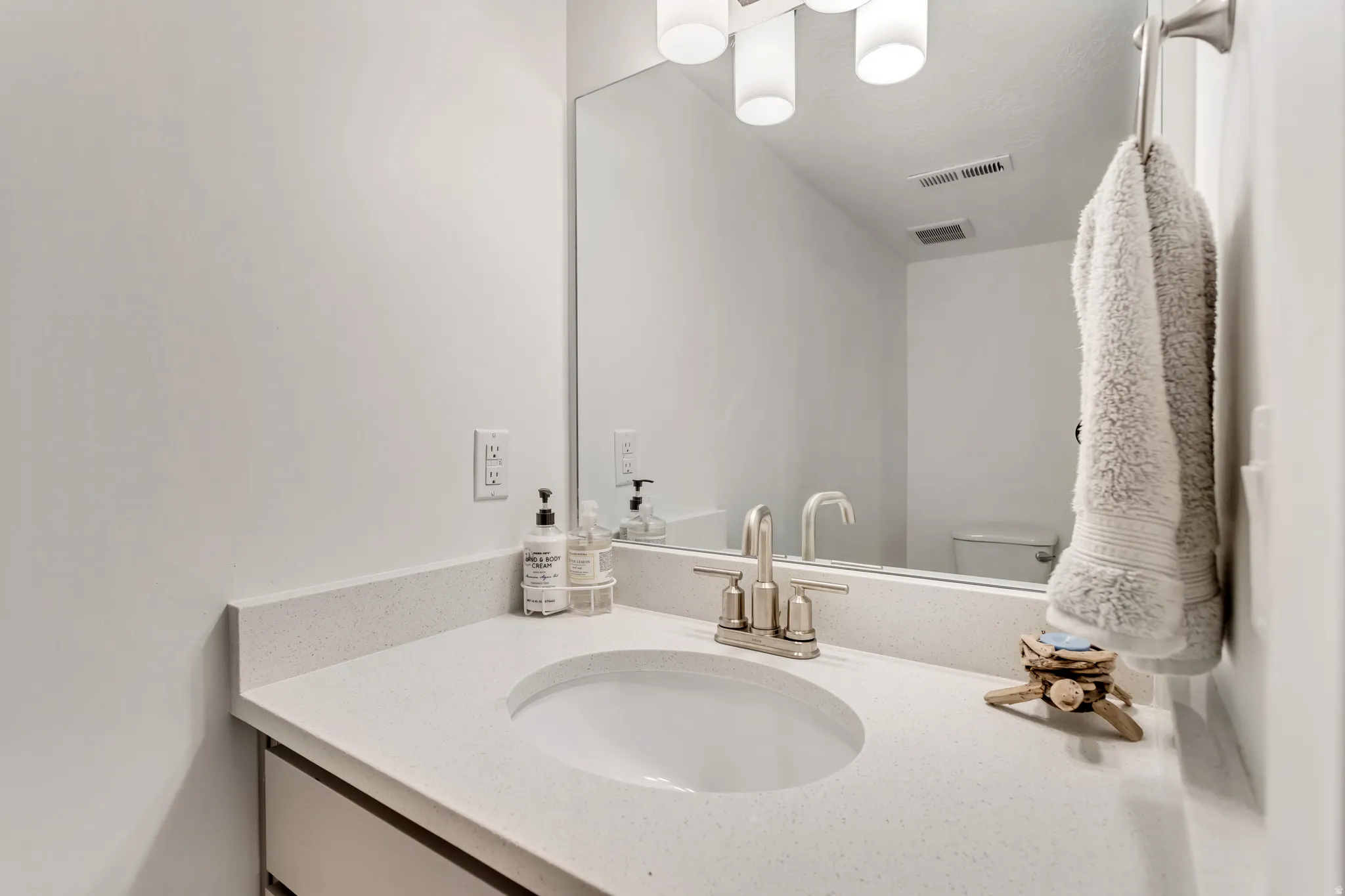 Integrated sink with a light-toned countertop, brushed nickel faucet, and a large wall-mounted mirror
