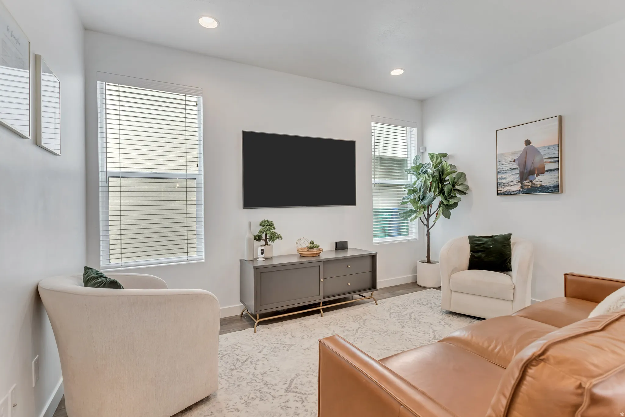 Recessed lighting illuminates the room, featuring two tall windows with blinds