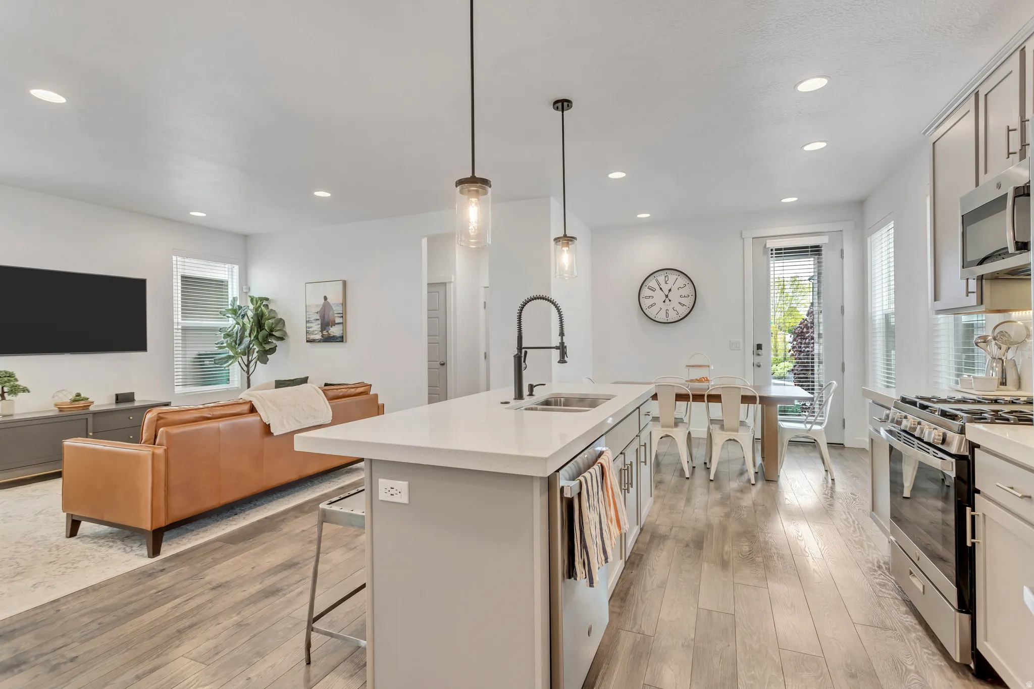Open-concept living space featuring wood-finish flooring, recessed lighting, and a kitchen island with pendant lighting