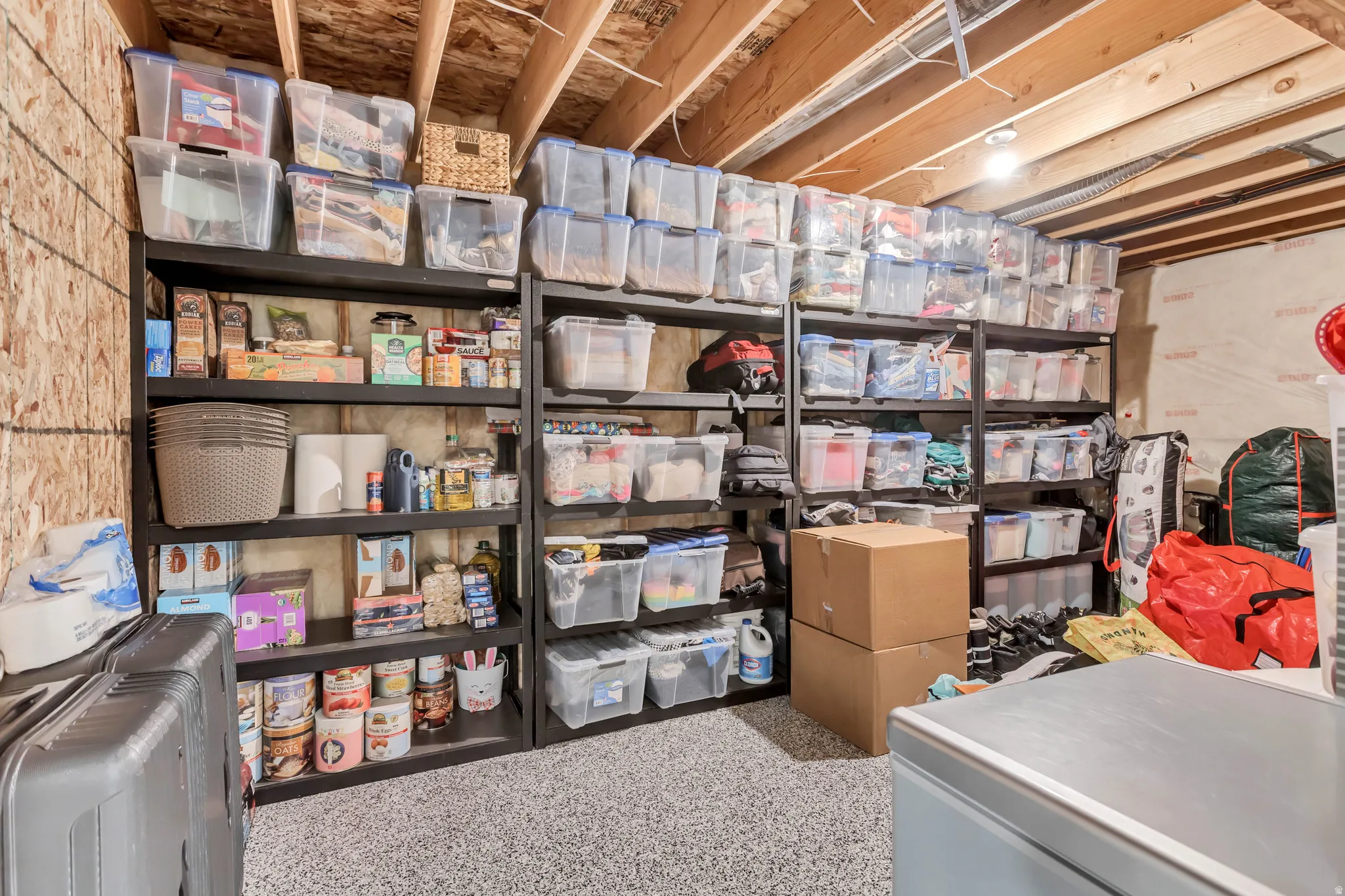 Utility space featuring exposed ceiling joists, durable composite flooring, and permanent shelving units
