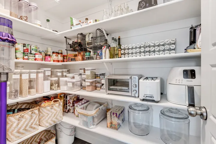 Customizable shelving offering extensive storage, white painted shiplap walls, and a white interior door with a brushed nickel knob