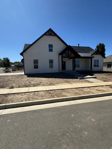 White board and batten exterior with dark trim accents, covered entry, and dark asphalt shingle roof