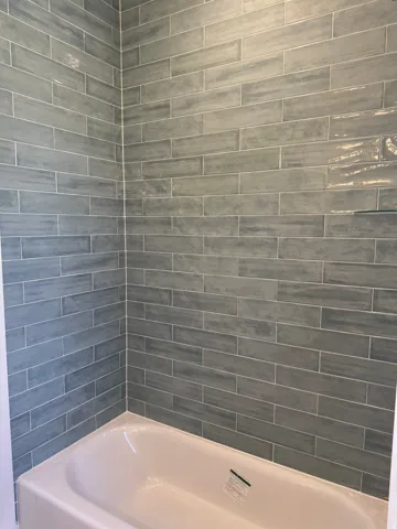 Bathtub with subway tile surround and a glass shelf