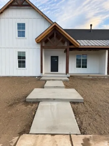 White board and batten siding, dark shingle roof, dark wood-finish porch columns, and a dark front entry door