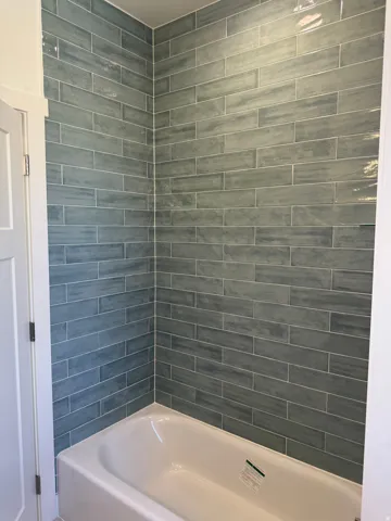 Bathtub with a tiled surround featuring rectangular blue-gray ceramic tiles