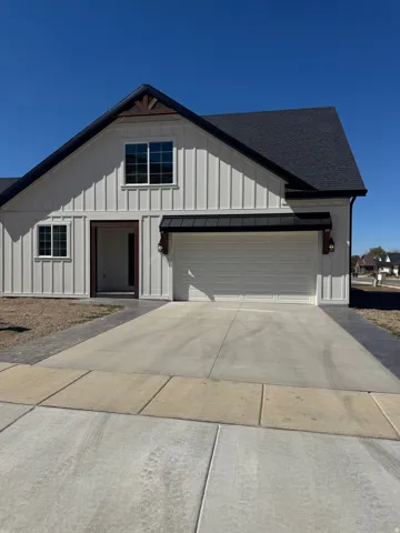 White vertical siding exterior with dark-shingled roof and integrated two-car garage