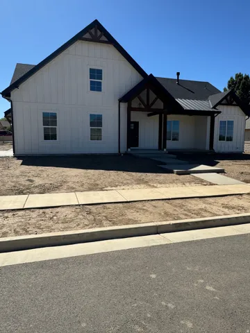 Contemporary farmhouse exterior with white board and batten siding, dark trim, a covered entry, and multiple windows