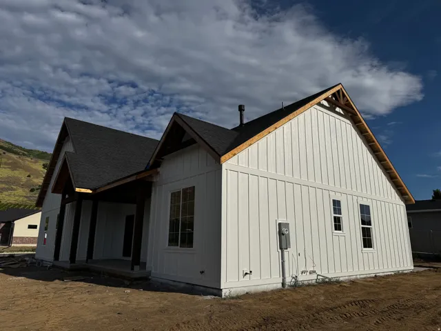 Board and batten siding, dark-toned roof, exposed wood rafter tails, multiple windows, covered entry
