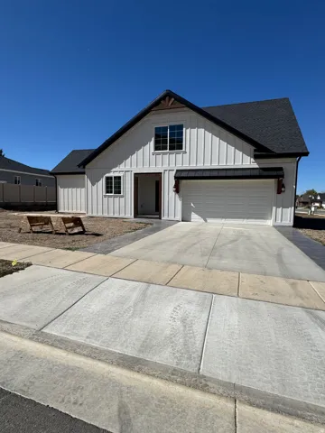 White board and batten exterior, dark shingle roof, attached garage with white door, wood beam accents