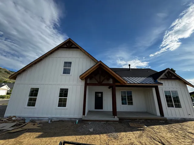 Board and batten siding, dark framed windows, covered entry porch, exposed timber porch supports, and a dark shingle roof