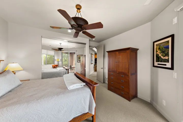 Ceiling fan with wooden blades, wall-to-wall carpeting, mirrored closet doors, and light gray walls