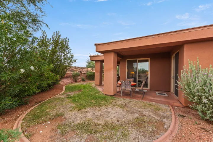 Covered patio with sliding glass door, finished concrete patio, and desert landscaping