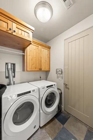 Wood cabinetry with dark hardware, a flush-mount ceiling light, and a panel door with a round knob